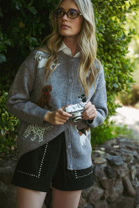 Woman holding a camera outdoors with greenery in the background