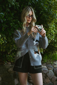 Woman taking a photo with a vintage camera against a green bush background