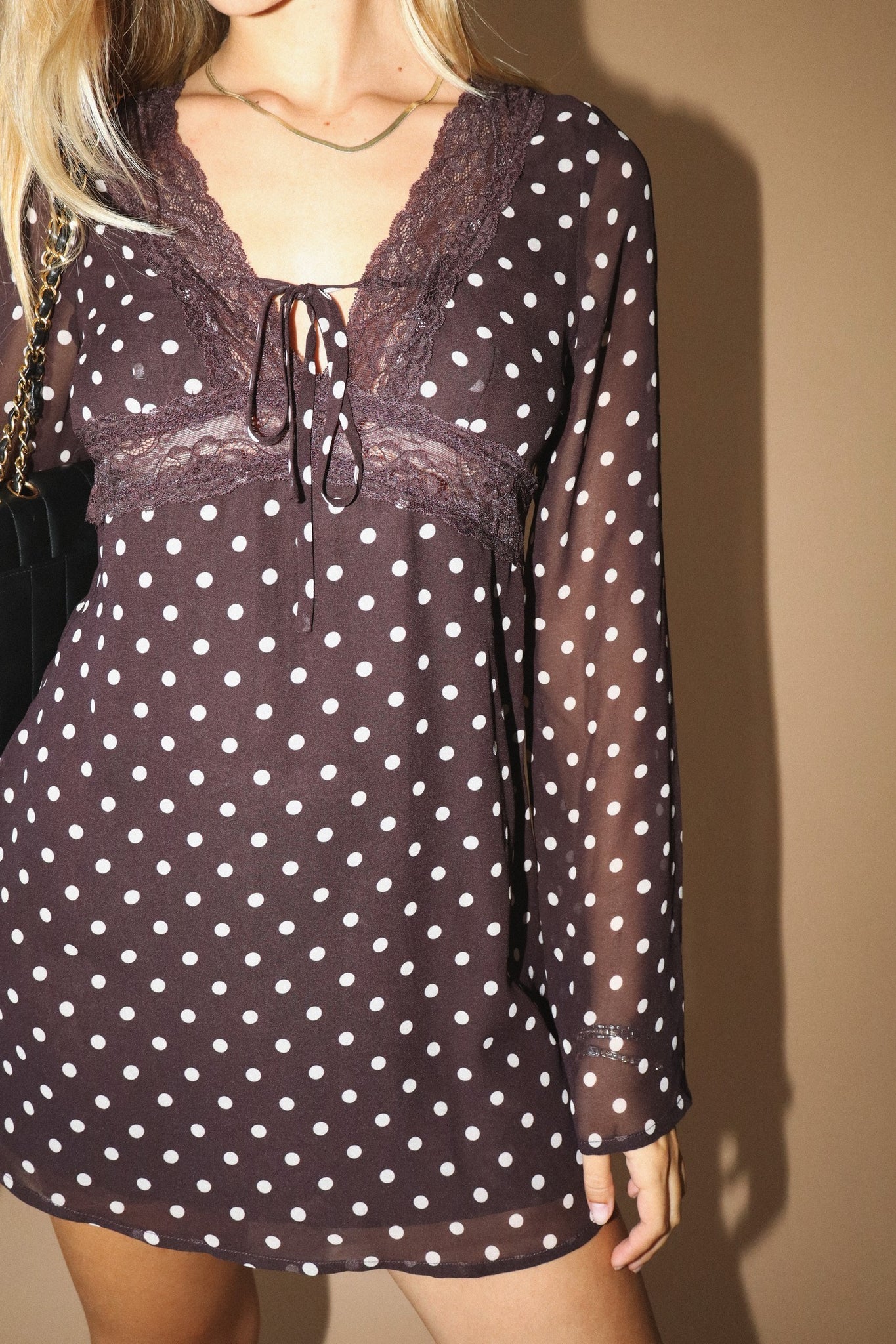 Polka dot dress with sheer long sleeves on a plain background