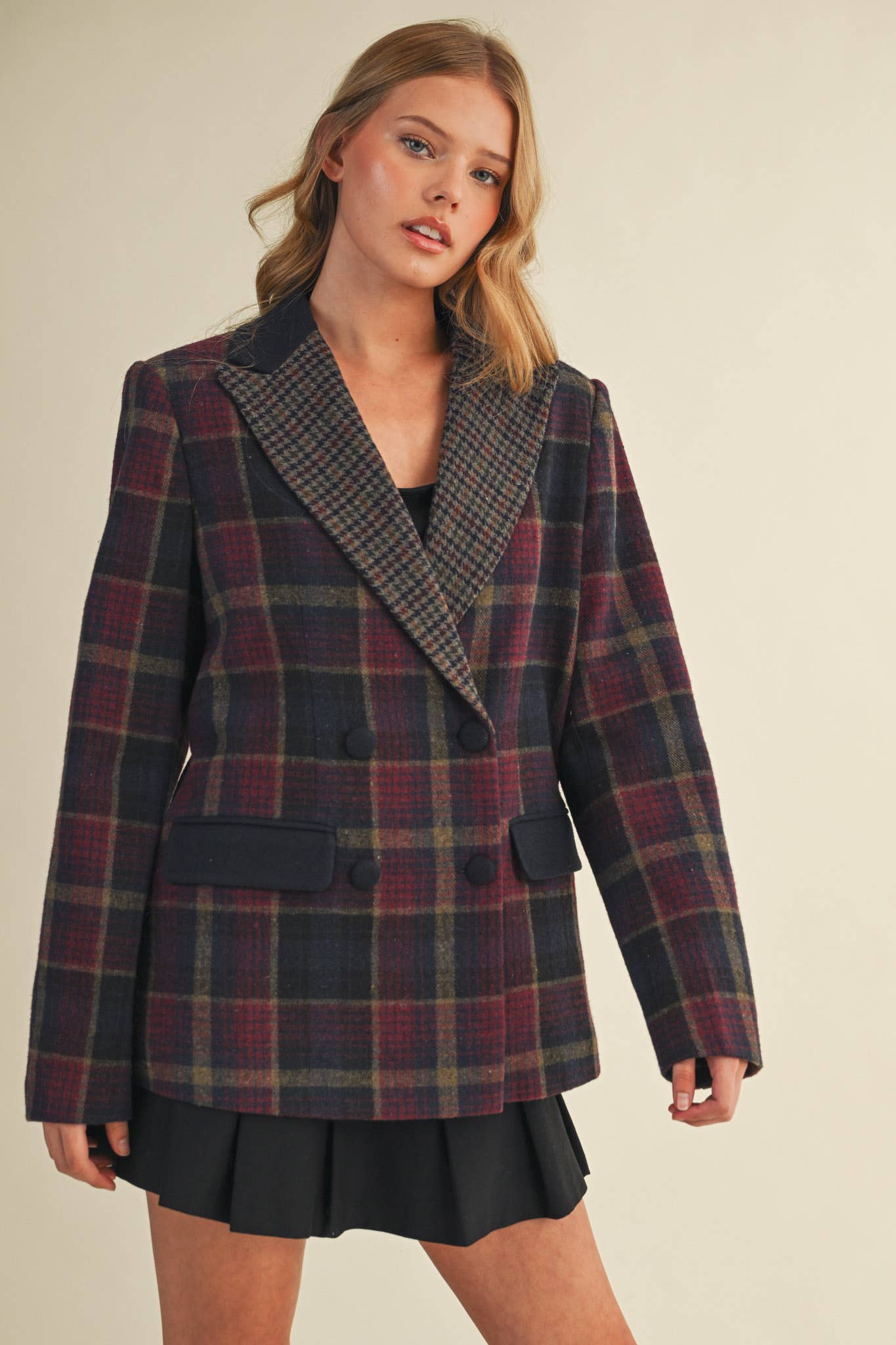 Woman wearing a plaid blazer and black skirt on a beige background
