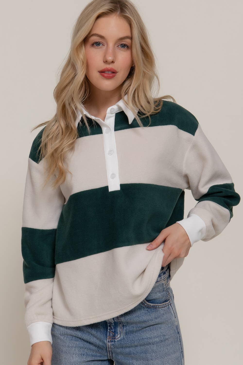 Woman wearing a color-blocked sweater with green and beige panels on a plain background