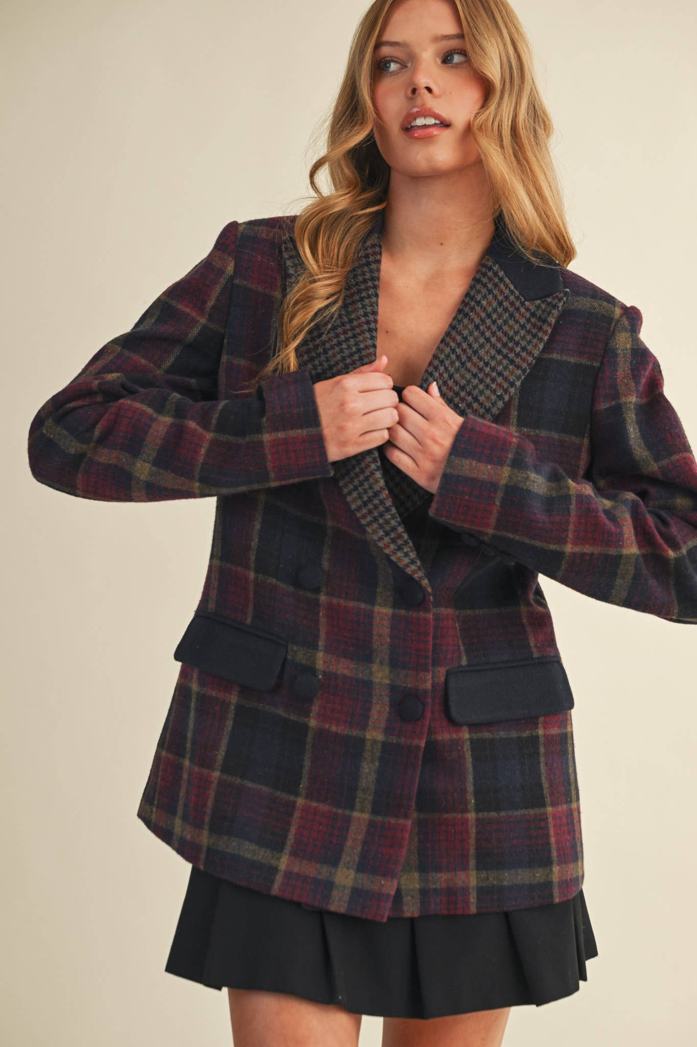 Woman wearing a plaid blazer over a black skirt on a beige background